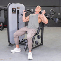 Thumbnail for Man using a shoulder press machine with an adjustable seat and pin selectorized weight stack.