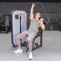 Thumbnail for Man using a shoulder press machine, pushing one handle up while the other is down.