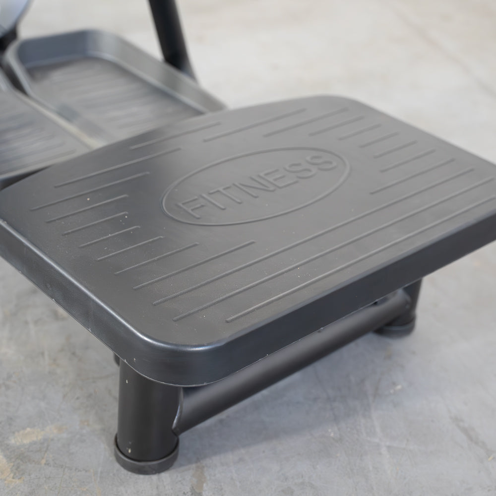 Close-up of a black fitness machine footplate with "FITNESS" embossed on it.