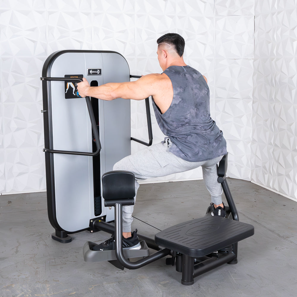 Man using a standing abductor machine, pushing outward with his legs against padded levers.