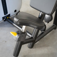 Thumbnail for Adjustable black padded seat with white stitching and yellow lever on a triceps extension machine.