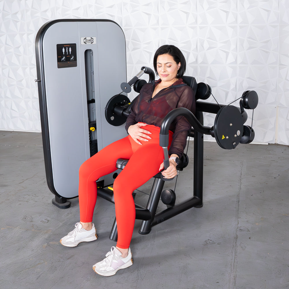 Woman in red leggings using a gray and black triceps extension machine.
