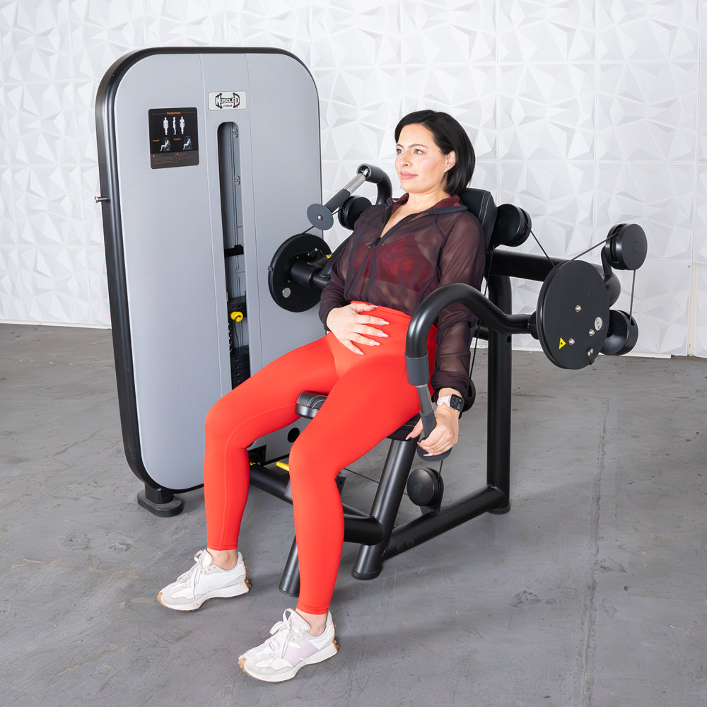 Woman in red leggings using a triceps extension machine with an adjustable seat.
