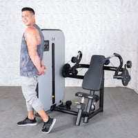 Thumbnail for Man in tank top stands next to a gray and black triceps extension machine with an adjustable seat.