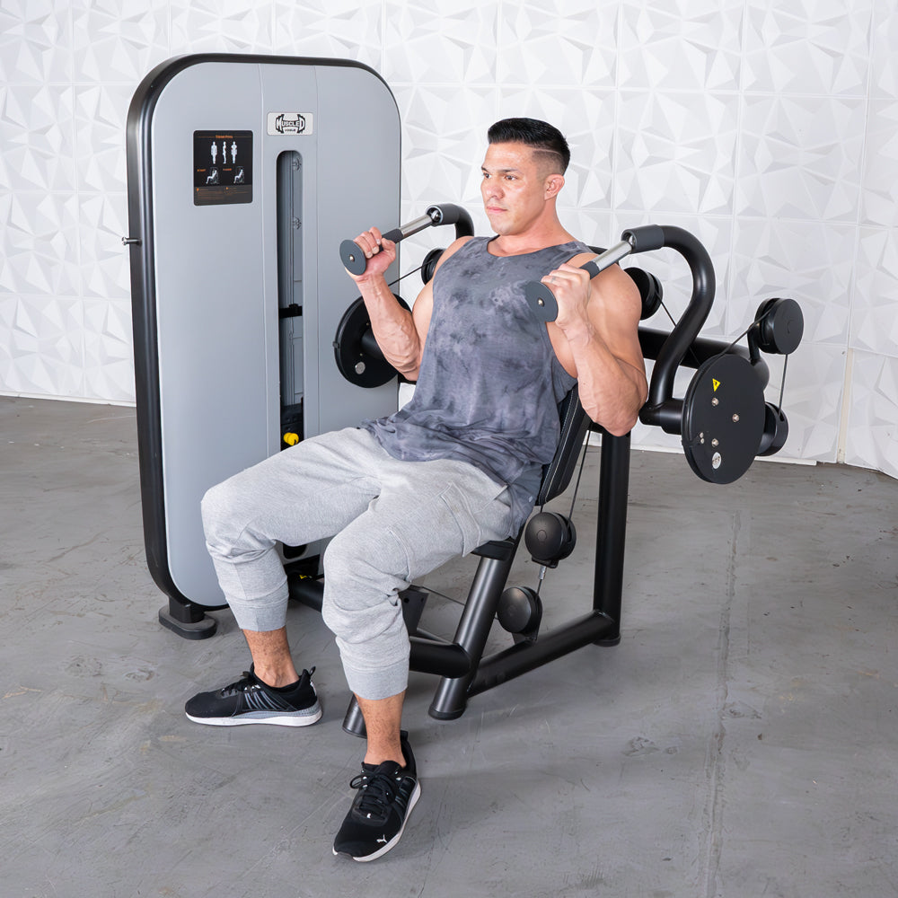 Man in a tank top and sweatpants using a triceps extension machine.