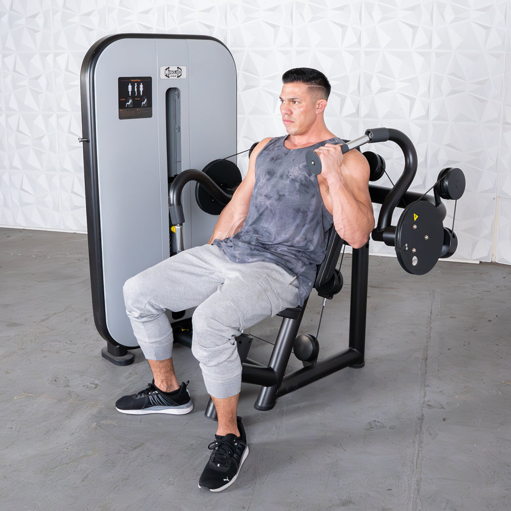Man using a triceps extension machine, seated with one arm extended, performing a workout.