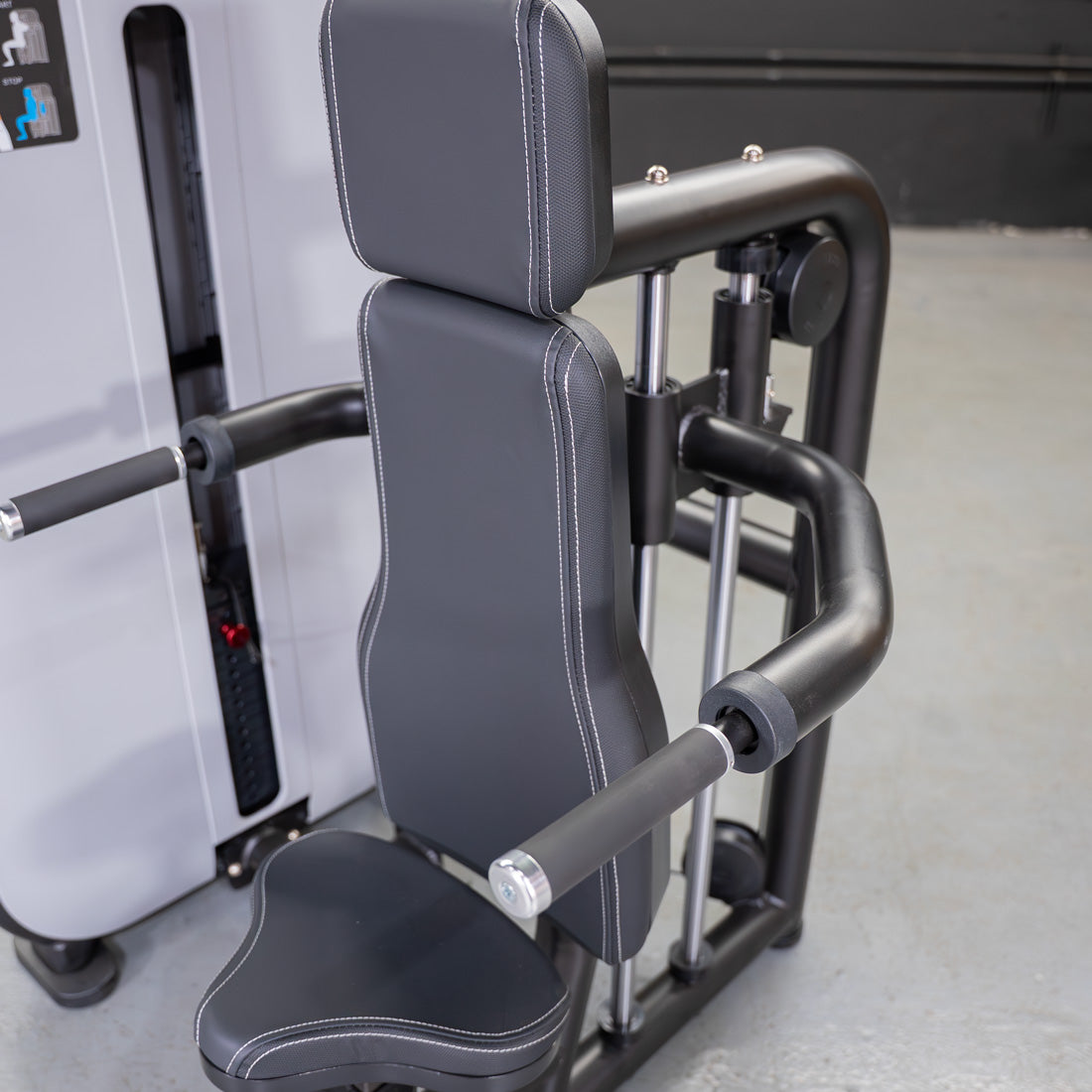 Close-up of a black triceps press-down machine with an adjustable seat and white stitching.