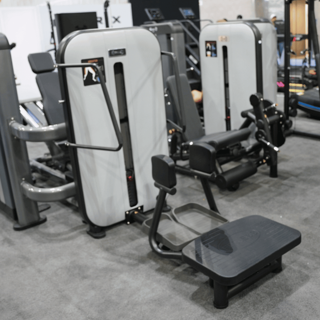 Gray and black standing abductor machine with a weight stack and foot platforms in a gym setting.
