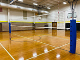 Blue volleyball standard pole pads on both net posts of a volleyball court in a school gym