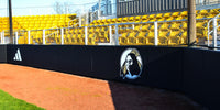 Thumbnail for Black backstop wall padding with a school logo in front of yellow stadium seats