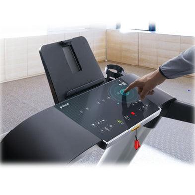 A hand adjusts the settings on a black treadmill console with an LED display, cup holder, and tablet stand.