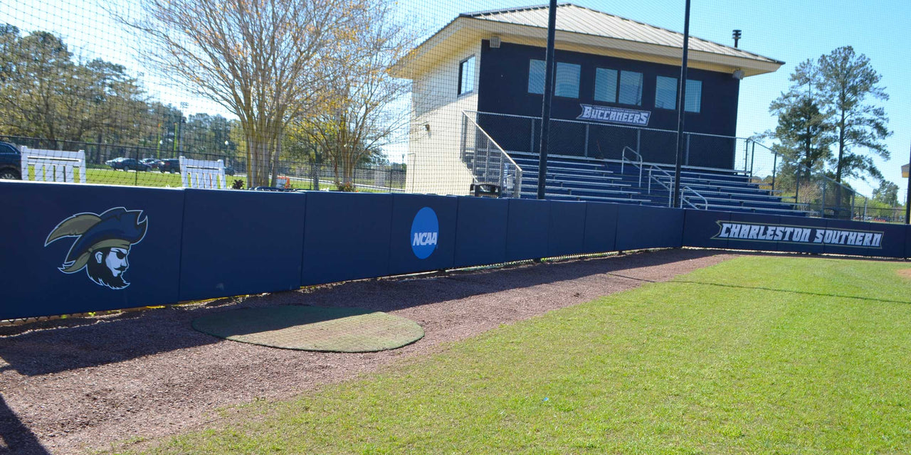 Navy backstop padding with a Buccaneers logo running behind home plate