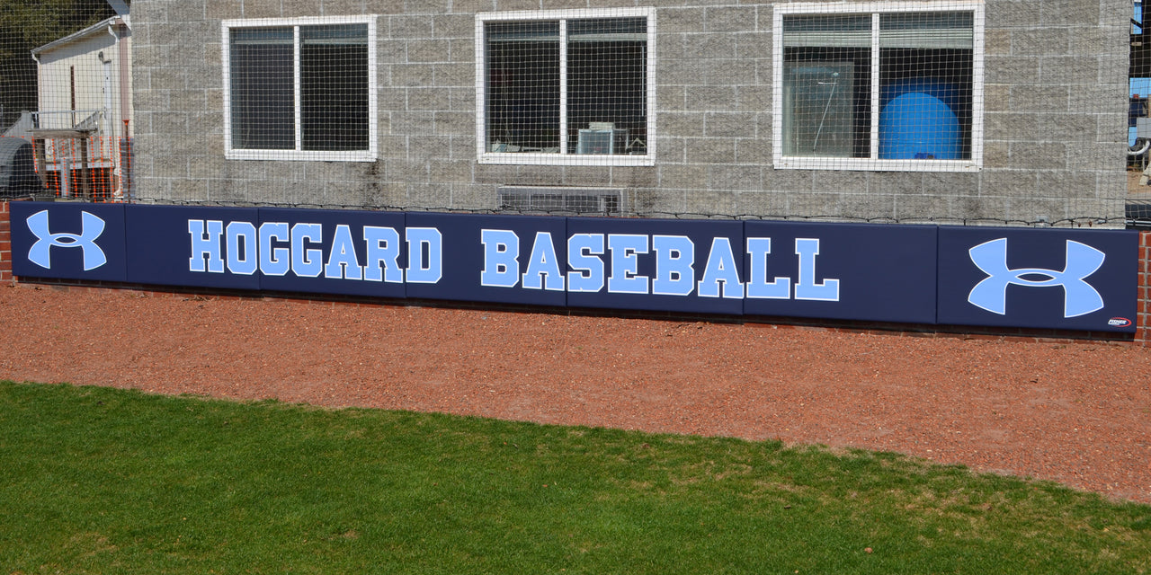 Navy backstop padding printed with Hoggard Baseball mounted on a block wall
