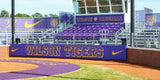 Purple folding backstop padding printed with Wilson Tigers behind home plate