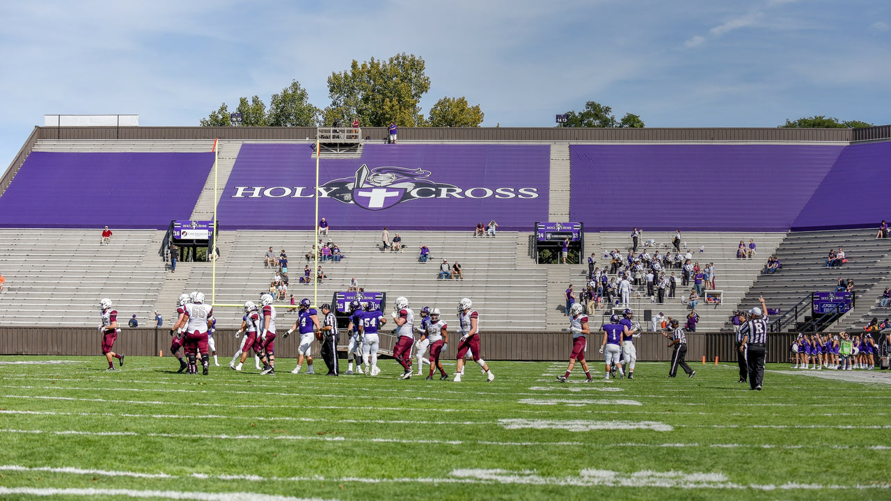 Purple custom stadium seat covers with Holy Cross graphics covering bleacher seating sections