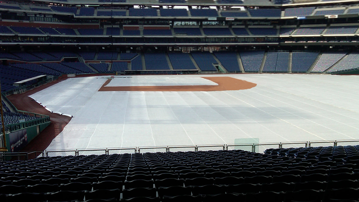 Citizens Bank Park stadium interior showing a CoverSports growth cover deployed across the outfield and infield turf of the Philadelphia Phillies MLB field, with the clay infield and pitcher's mound left exposed and empty blue seating visible in the background