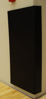 Black corner wall pad installed on a light-colored brick wall, with a wooden floor visible at the bottom.
