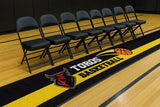 Black and yellow custom logo floor mat reading Toros Basketball with a red bull logo beside a row of bench chairs