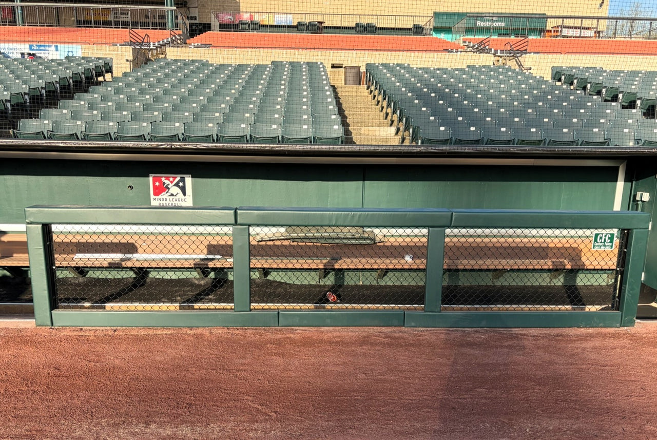 Green custom fence rail and post padding installed on a dugout rail at a baseball stadium