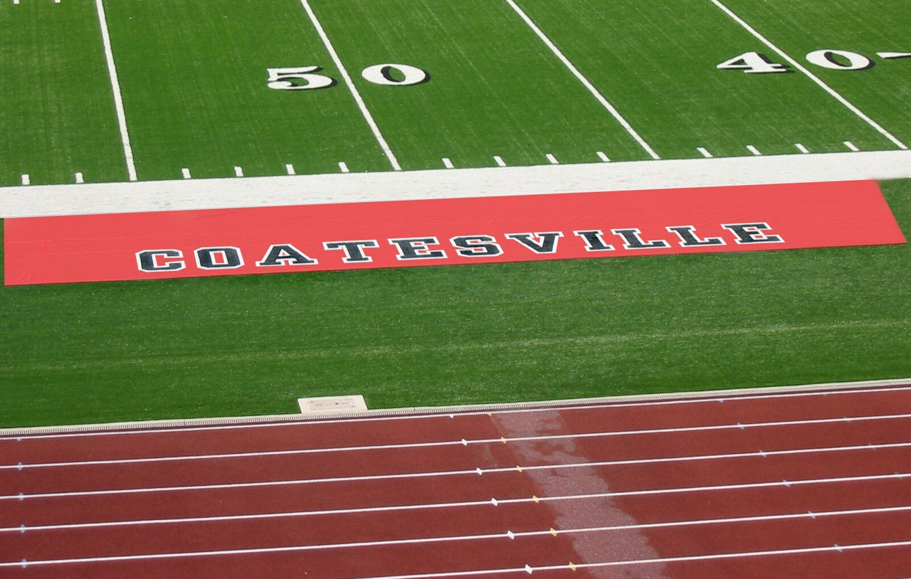 Red custom football sideline tarp with Coatesville team name graphics protecting field sideline turf