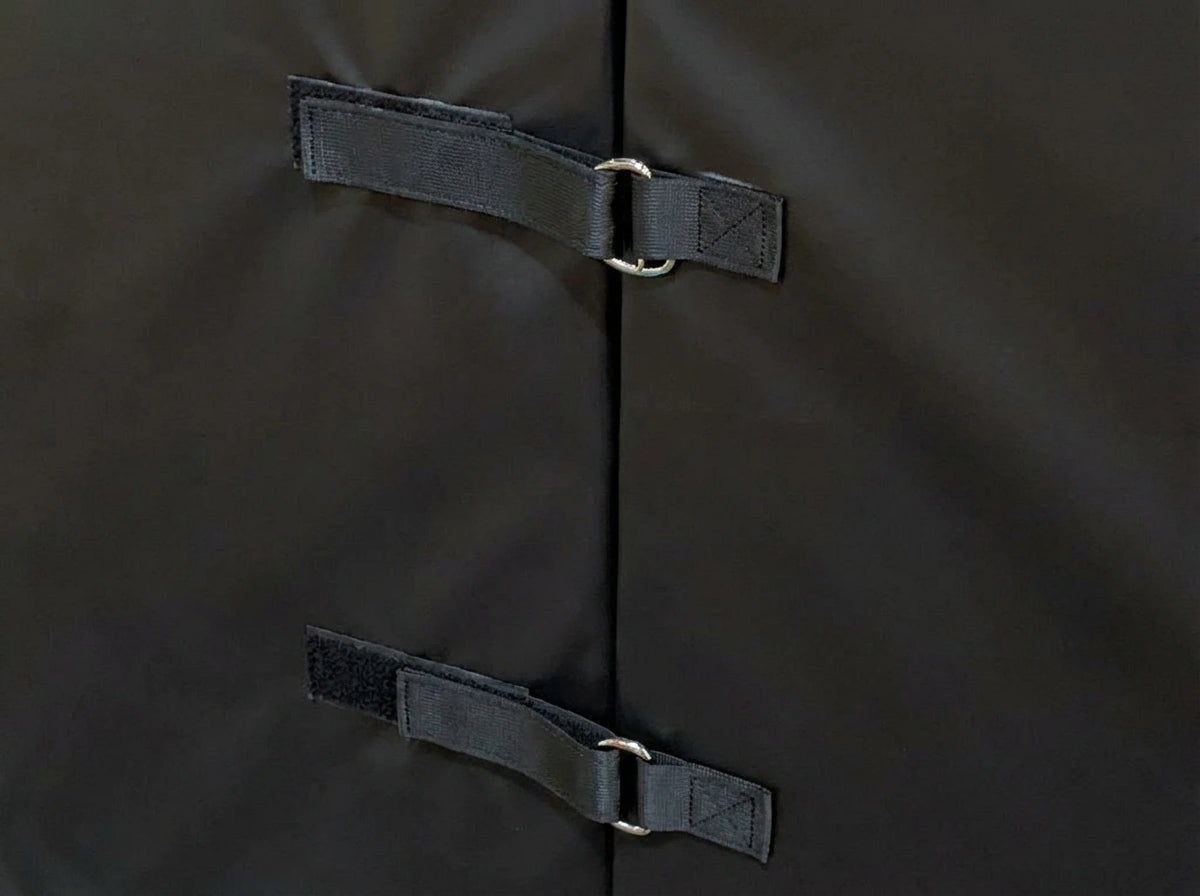 Close-up detail of black divider pad showing velcro attachment straps and metal D-ring hardware used to connect multiple barrier pads together for modular gym partitions and space division