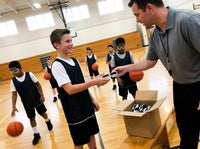 Thumbnail for Basketball coach handing a pair of dribble goggles from a box of team pack goggles to a youth player in the gym