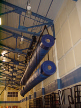 Two long blue rolled mats suspended from a ceiling track system in a gym.