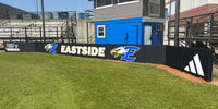 Thumbnail for Black backstop padding printed with Eastside and eagle logos at a high school field