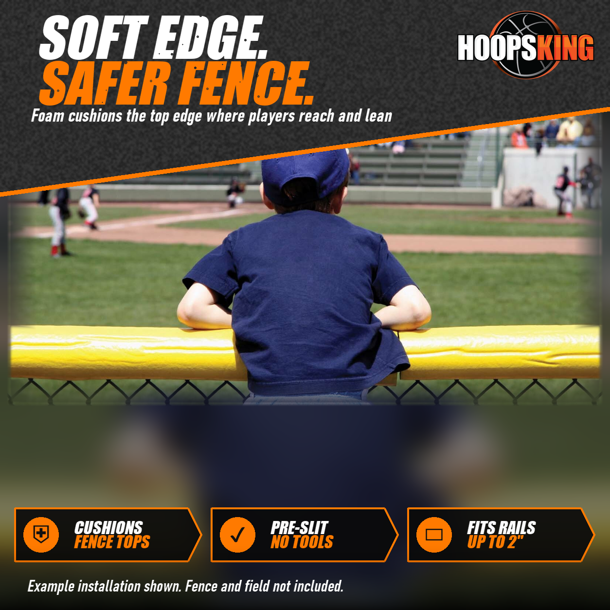 Young fan in a navy cap leaning on yellow SafeFoam padding on top of a chain-link outfield fence during a game