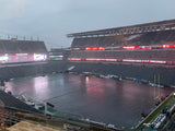 Black football field cover protecting the entire playing surface at Lincoln Financial Field during heavy rain at dusk