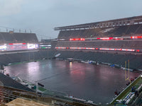 Thumbnail for Black football field cover protecting the entire playing surface at Lincoln Financial Field during heavy rain at dusk