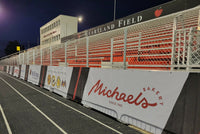 Thumbnail for Football windscreens printed with Michael's Bakery and other sponsor logos along a stadium track at Heartland Field