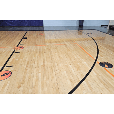 Basketball court with orange and black numbered spot markers on the floor.