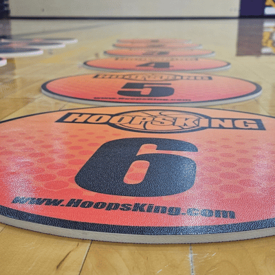 Orange and black numbered spot markers on a wooden basketball court floor.