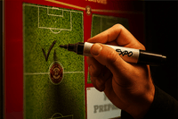 Thumbnail for Hand holding an Expo marker, drawing a checkmark on a soccer field whiteboard with a team logo.