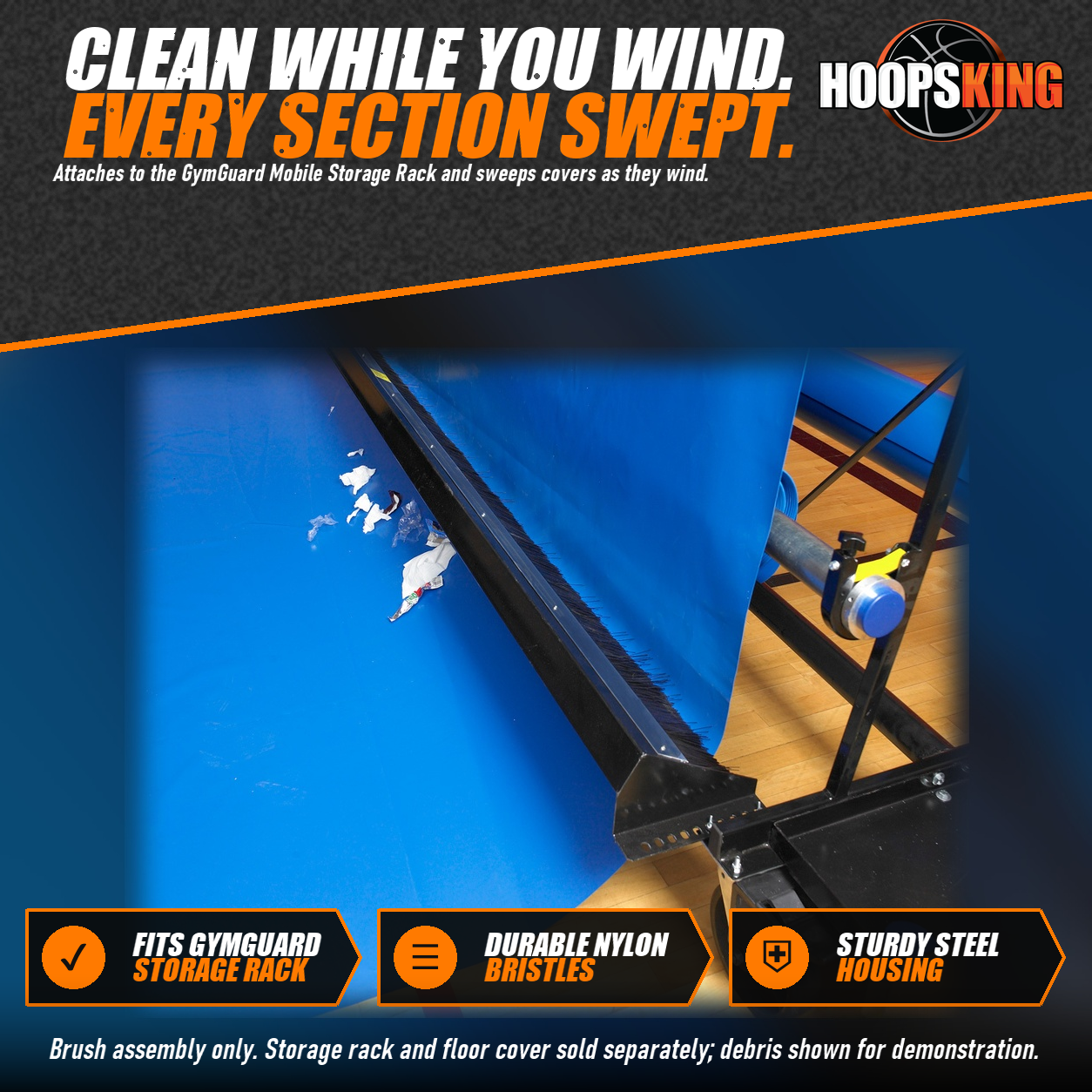 Black steel-housed nylon brush assembly mounted on a GymGuard storage rack, sweeping debris off a royal blue gym floor cover