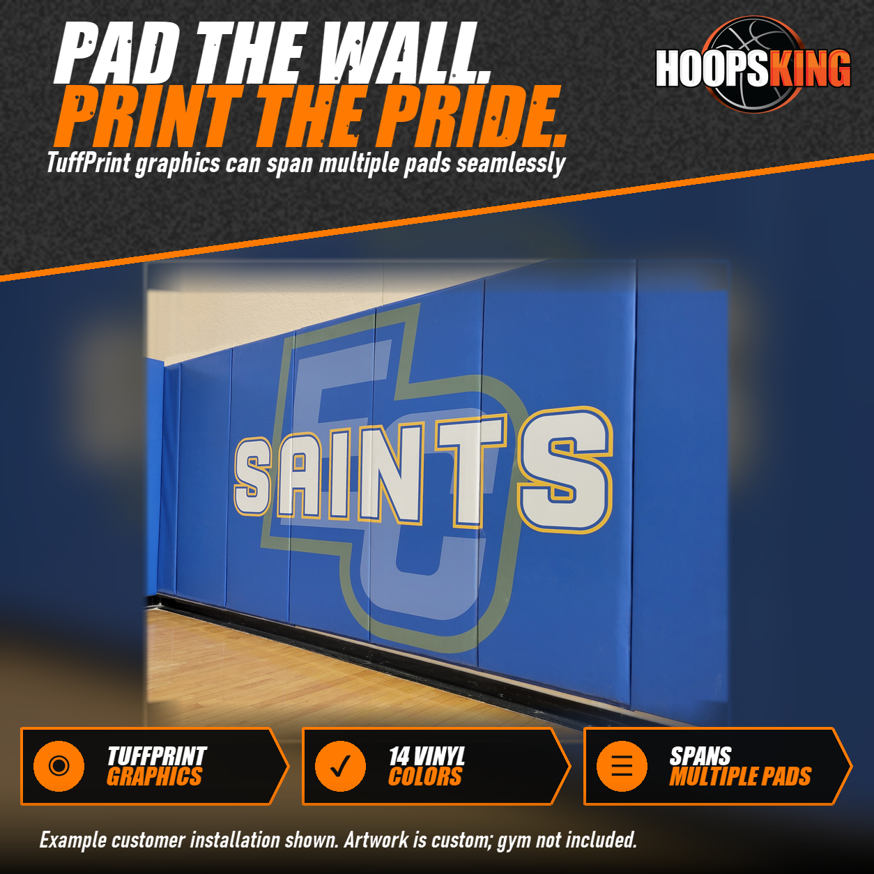 Blue gym wall pads printed with a large Saints wordmark over a pale logo along a hardwood gymnasium floor