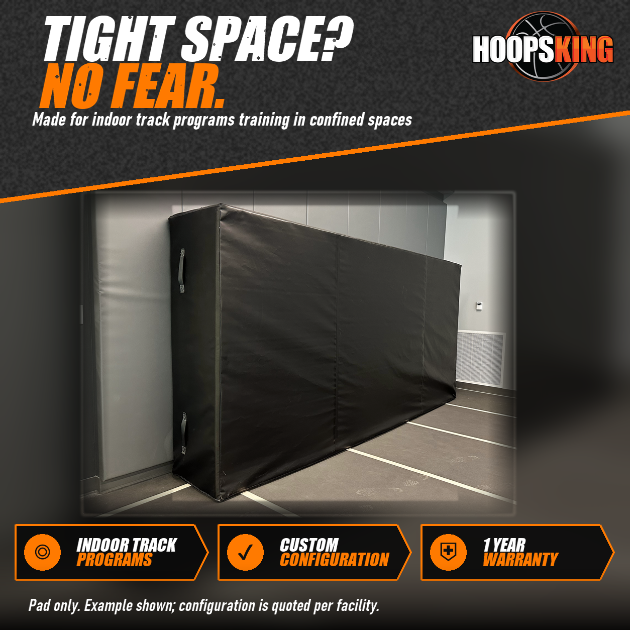Black extra-thick indoor track crash pad with side carry handles standing upright against a gray padded wall