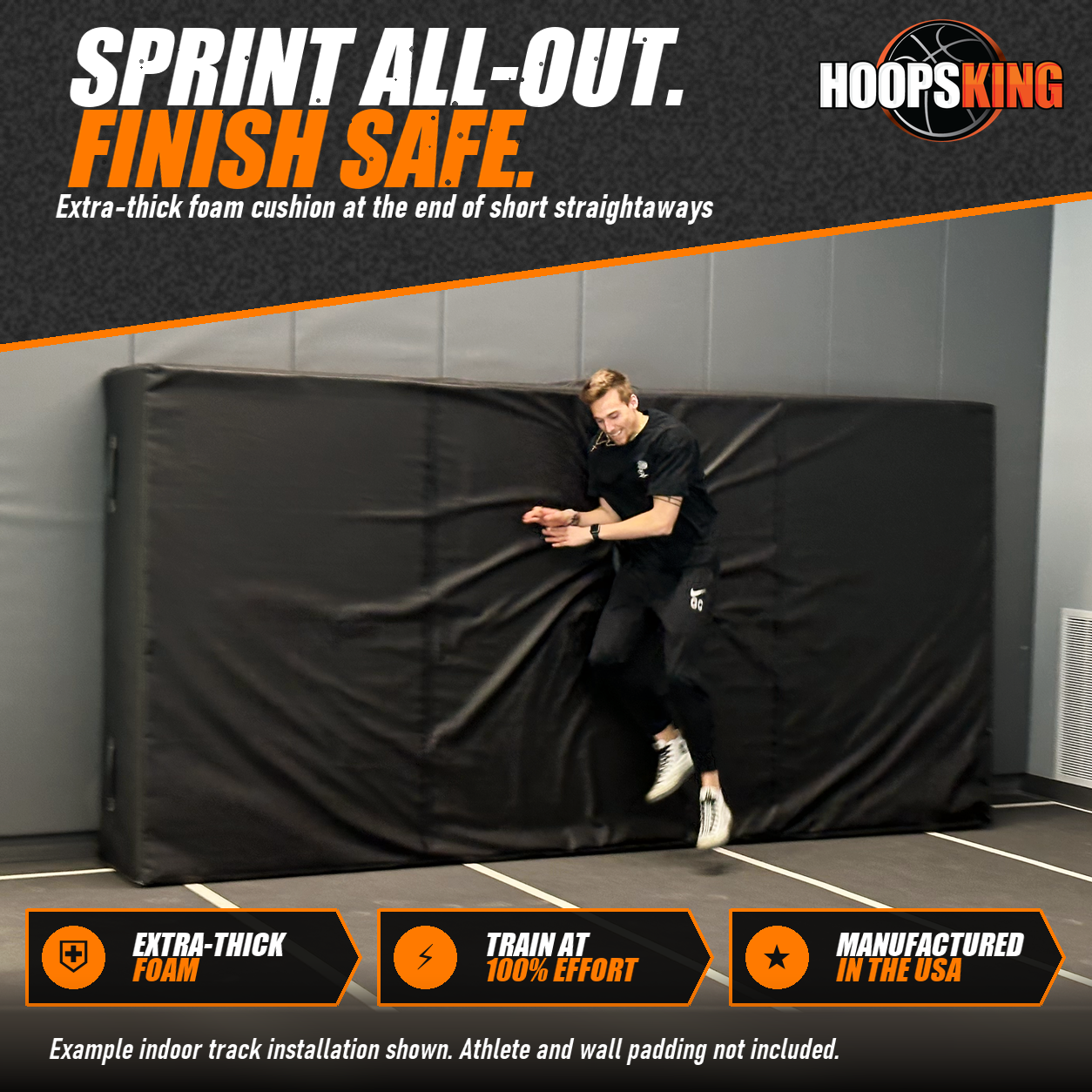 Athlete in black jumping into a tall black crash pad standing against the wall at the end of an indoor track lane
