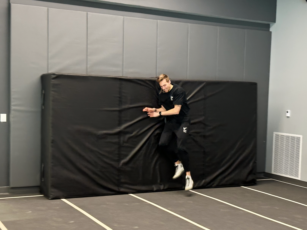 Black indoor track pad with high-density foam core for pole vault and high jump training