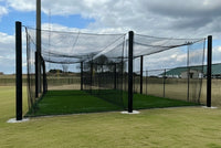 Thumbnail for Outdoor baseball cage with black steel poles, cable-suspended netting, and artificial turf installed at a school baseball field