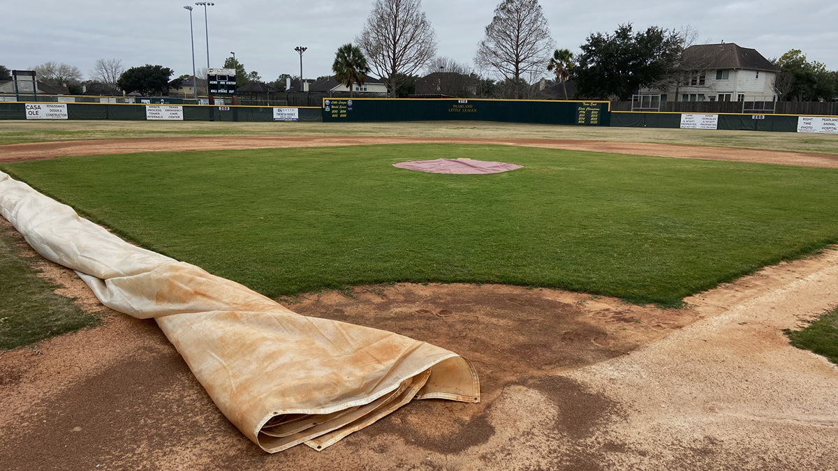 Pearland Little League's Major Field infield in winter: a CoverSports growth cover partially retracted along the third base line to allow mid-winter mowing of actively growing Seashore Paspalum turf
