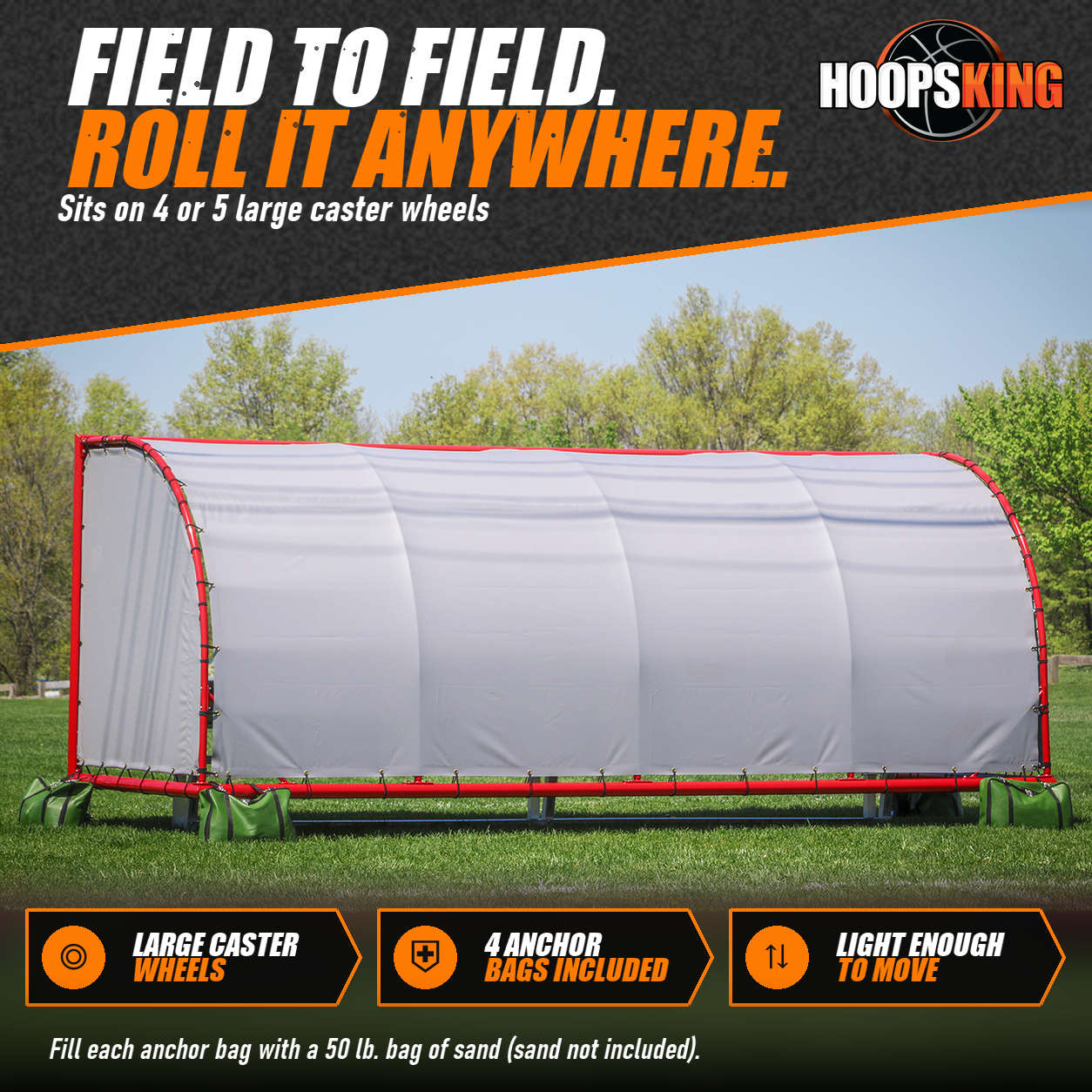 Side view of a portable team shelter with a red frame and white vinyl covering, anchored by green bags on a grass field