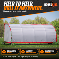 Thumbnail for Side view of a portable team shelter with a red frame and white vinyl covering, anchored by green bags on a grass field
