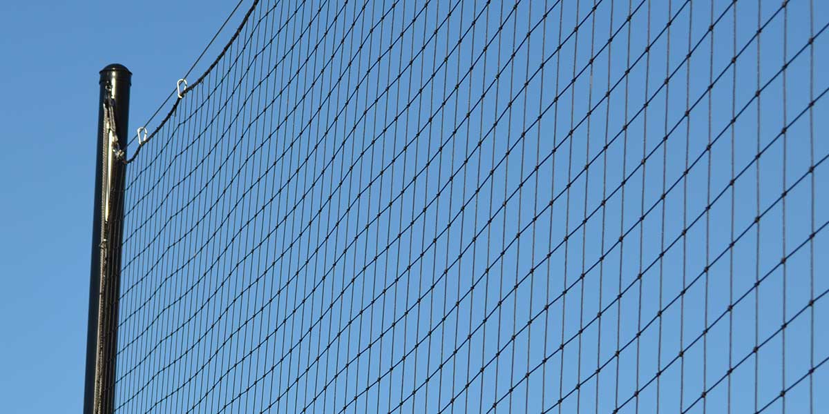 Black netting attached to a pole against a clear blue sky.