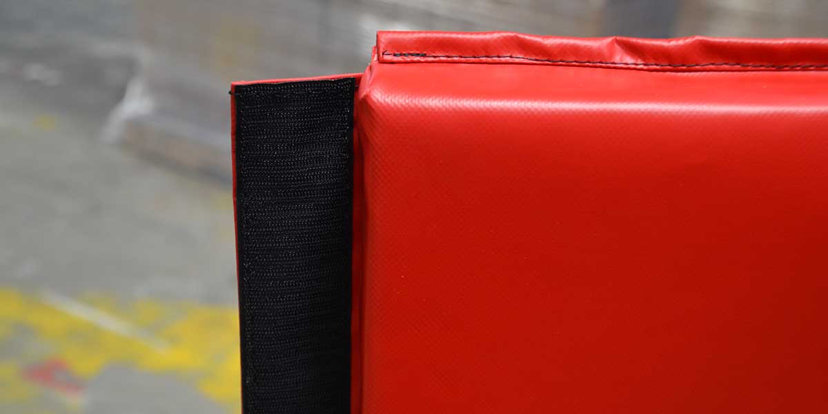 Close-up of a red mat with black hook-and-loop fastener on the side.