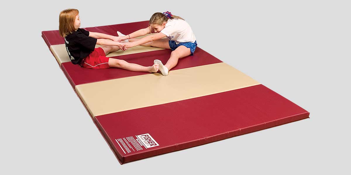 Two girls stretching on a red and tan folding urethane mat.
