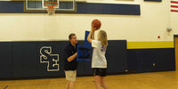 Thumbnail for Man holding a blue basketball L shield while a girl shoots a basketball.