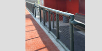 Thumbnail for Dark green padded rails with netting on a baseball field, red dugout in background.