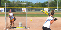 Thumbnail for Softball pitcher behind a protective net, throwing to a batter.